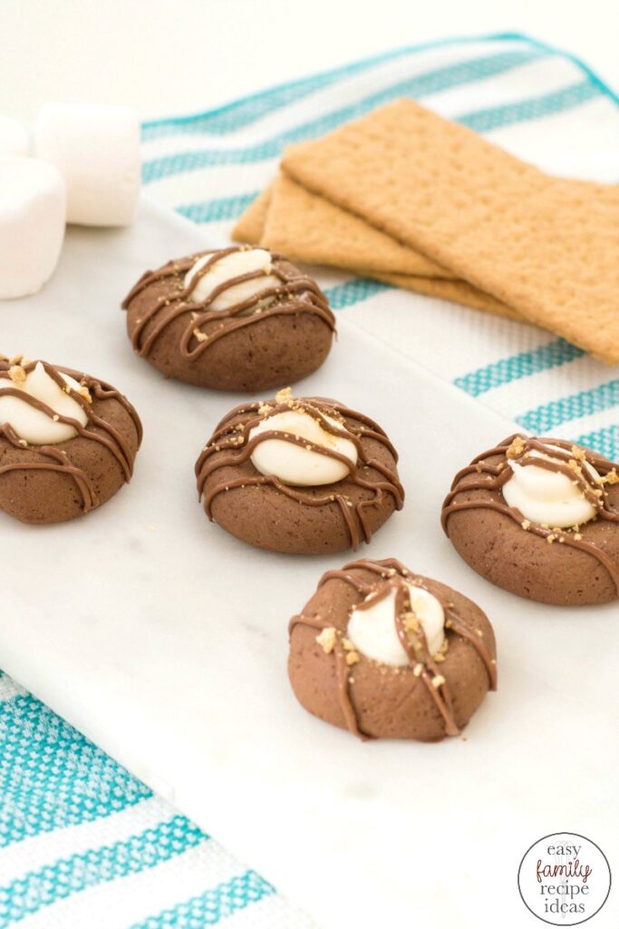 These S'mores Thumprint Cookies are the most delicious cookies and a great winter and fall treat! Great tasting S'mores Cookies are a simple thumbprint cookie kicked up a notch with fluffy marshmallow and chocolate. S'mores Cookies with Graham Crackers make perfect campfire cookies
