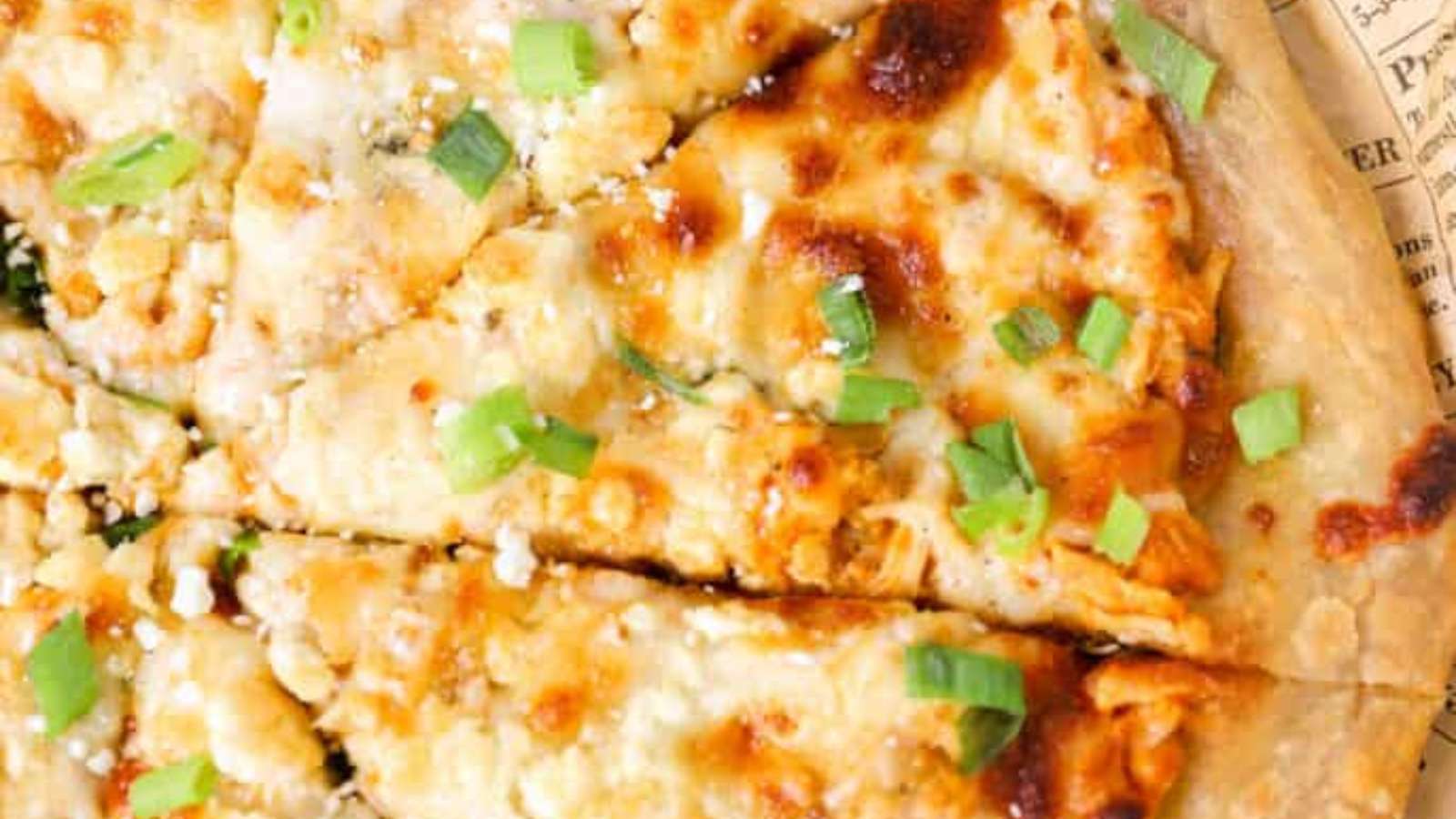 A pizza with chicken and green onions on top.