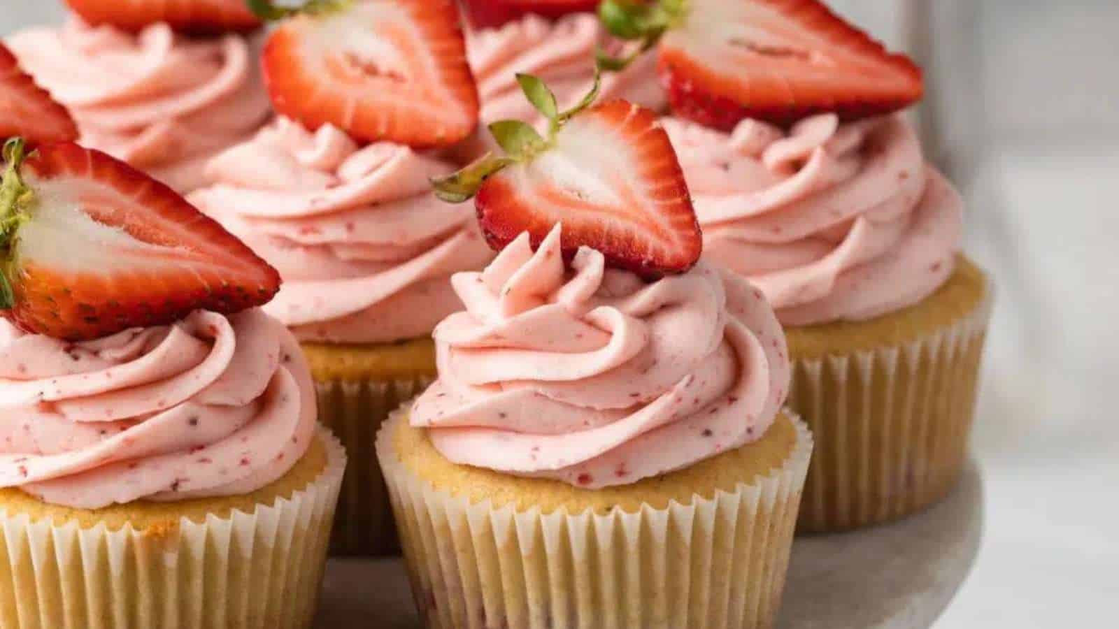 Strawberry cupcakes topped with whipped cream and strawberries.