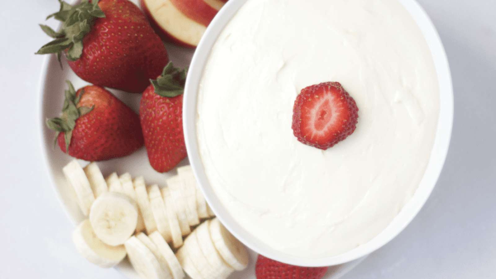 A bowl of fruit dip with strawberries and bananas.