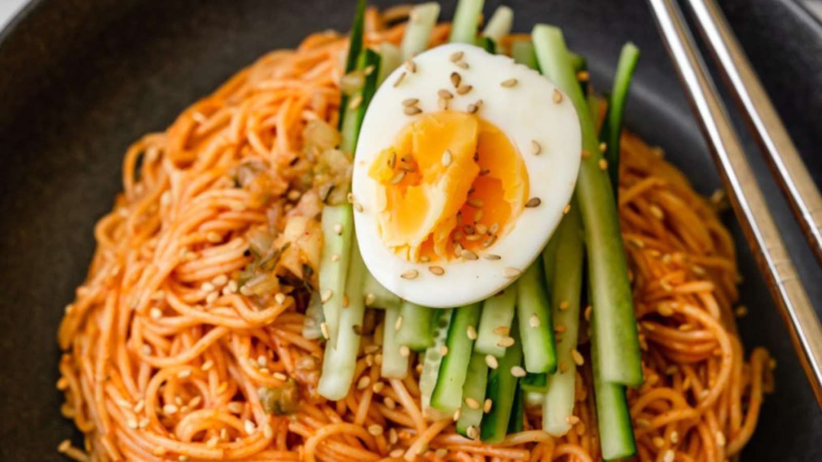 A bowl of noodles with an egg on top (Bibimmyeon).