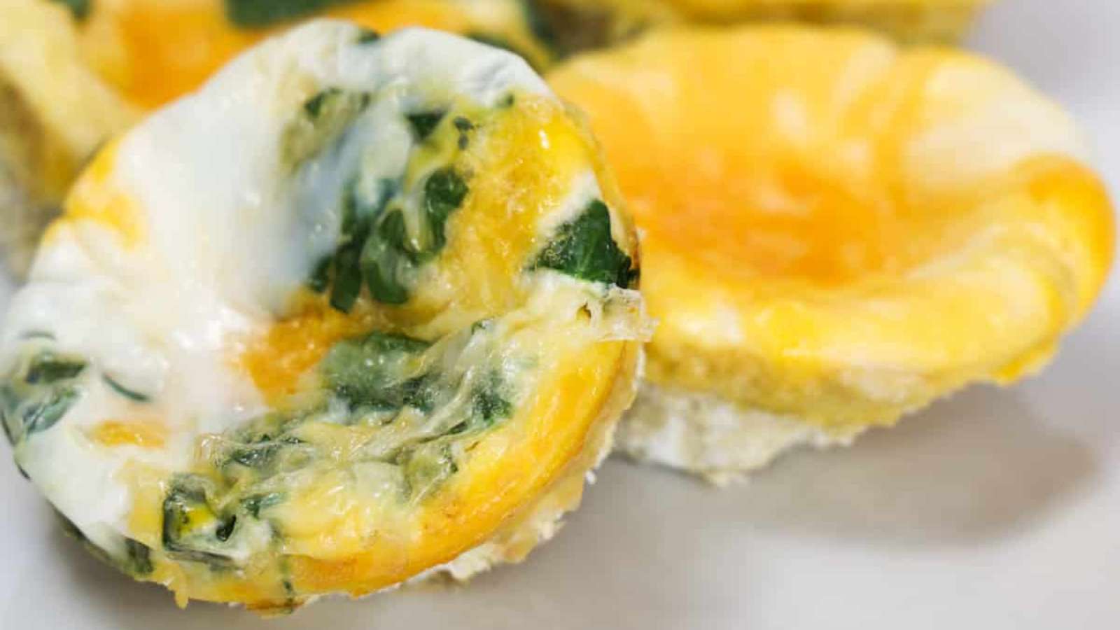 Egg muffins with spinach and cheese on a white plate.