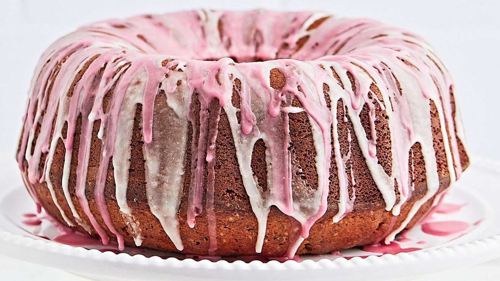 A pink mulled wine bundt cake with icing on top.