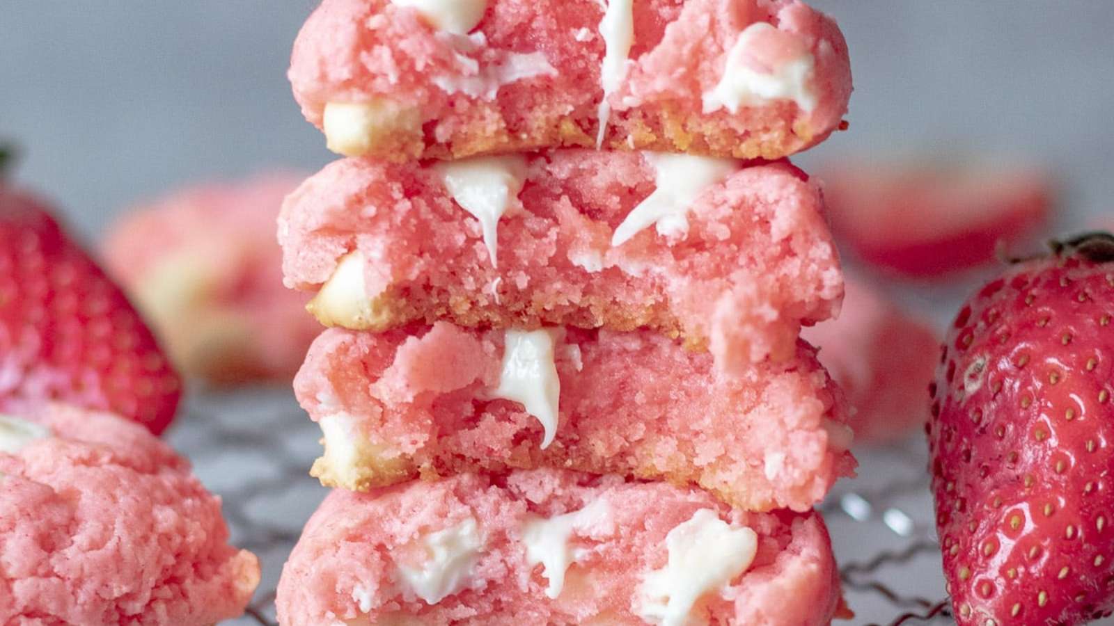 A stack of pink cookies with strawberries.