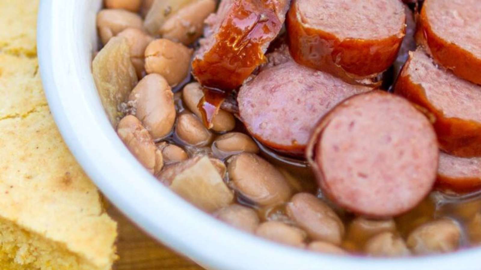 A bowl of beans, sausage and cornbread.