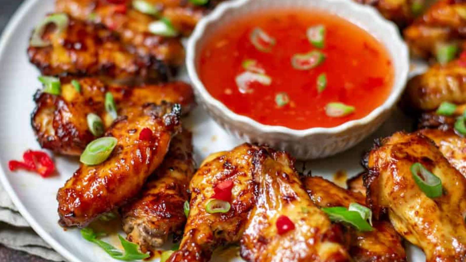 Asian chicken wings with dipping sauce on a plate.