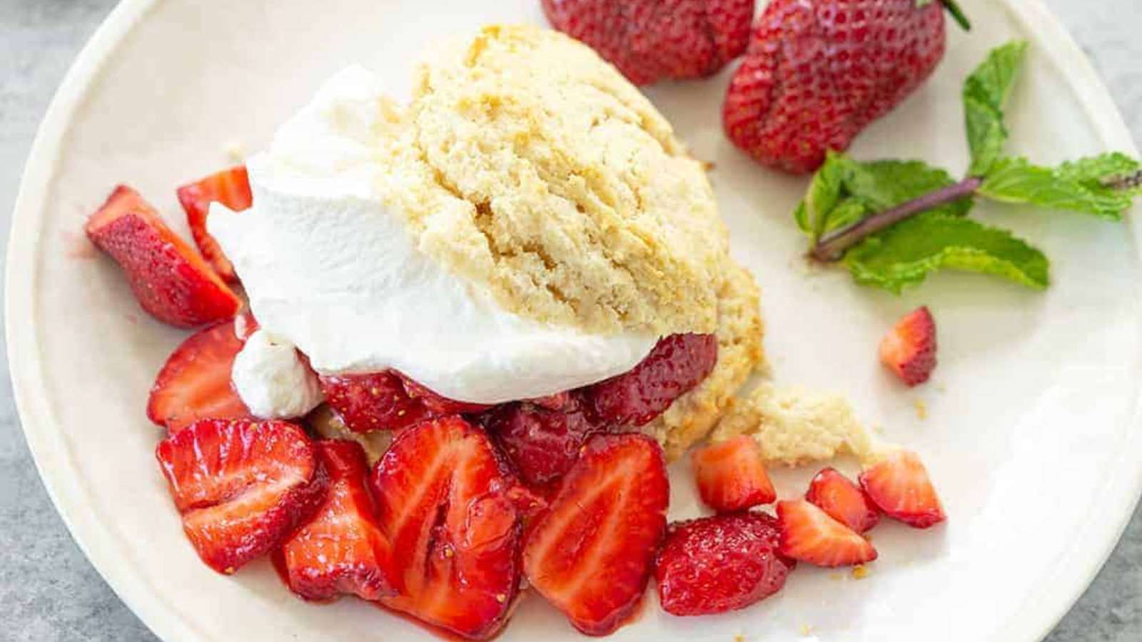 A white plate with strawberries, cake and whipped cream.