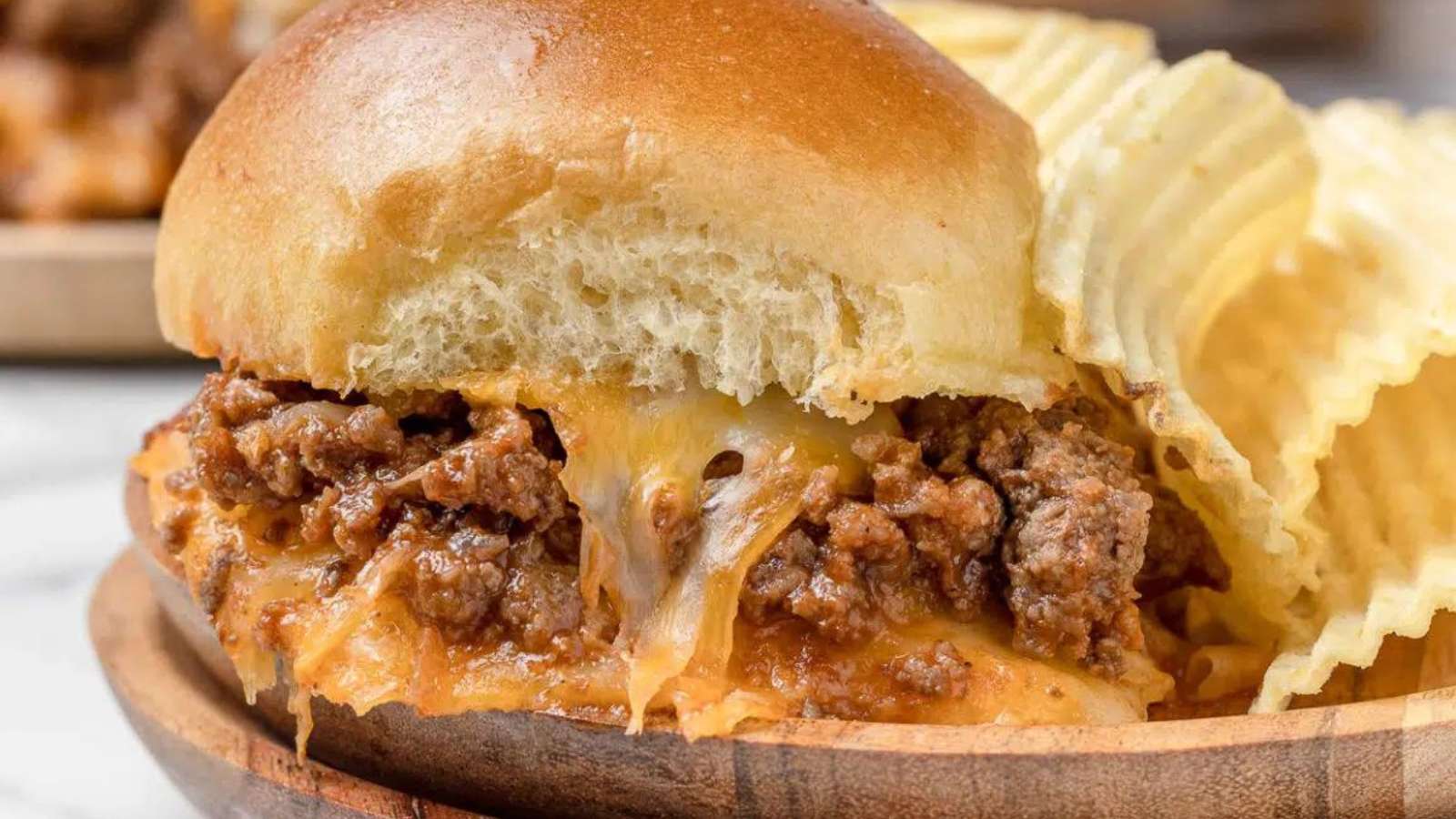 A bowl of cheesy beef pot sliders on a plate.