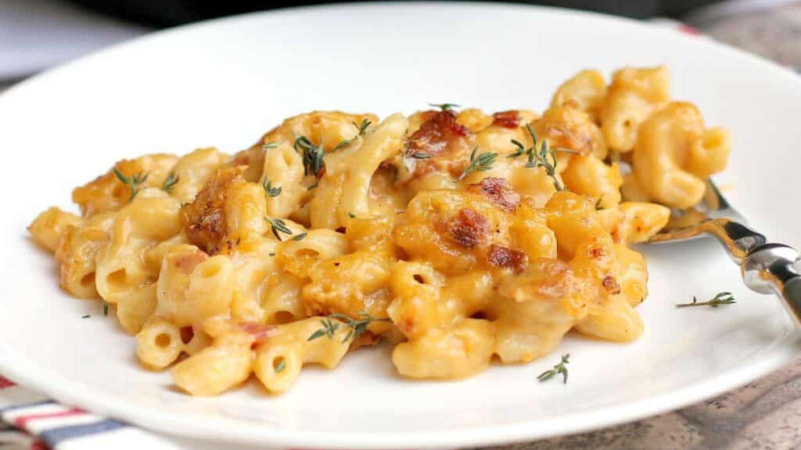 Macaroni and cheese with bacon and thyme, enhanced with the rich flavors of Guinness beer, served on a white plate.