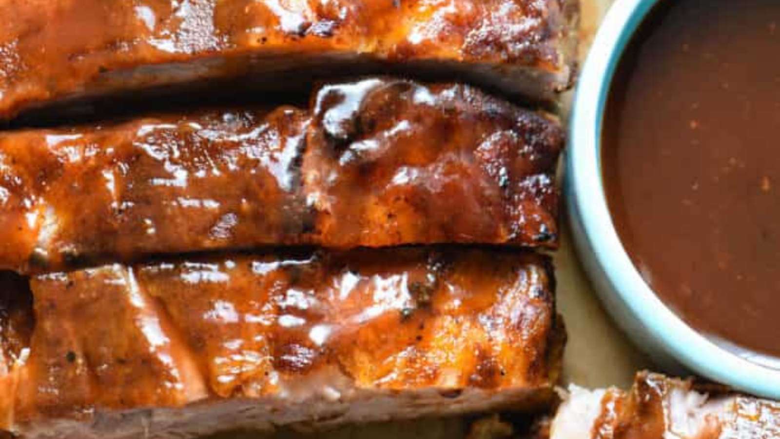BBQ ribs with BBQ sauce on a wooden cutting board.