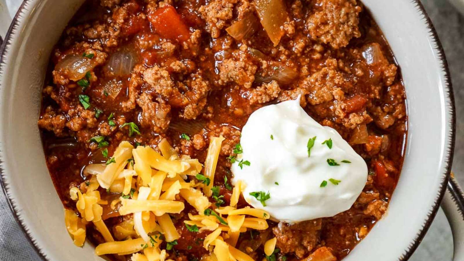 A bowl of chili with sour cream and cheese, made with Guinness beer.