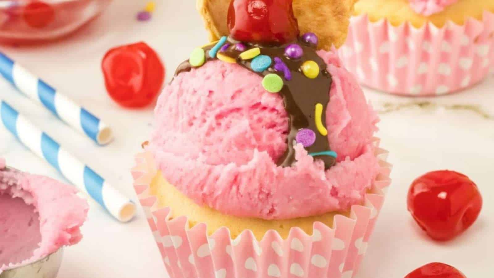 Pink ice cream cupcakes with cherries and sprinkles.