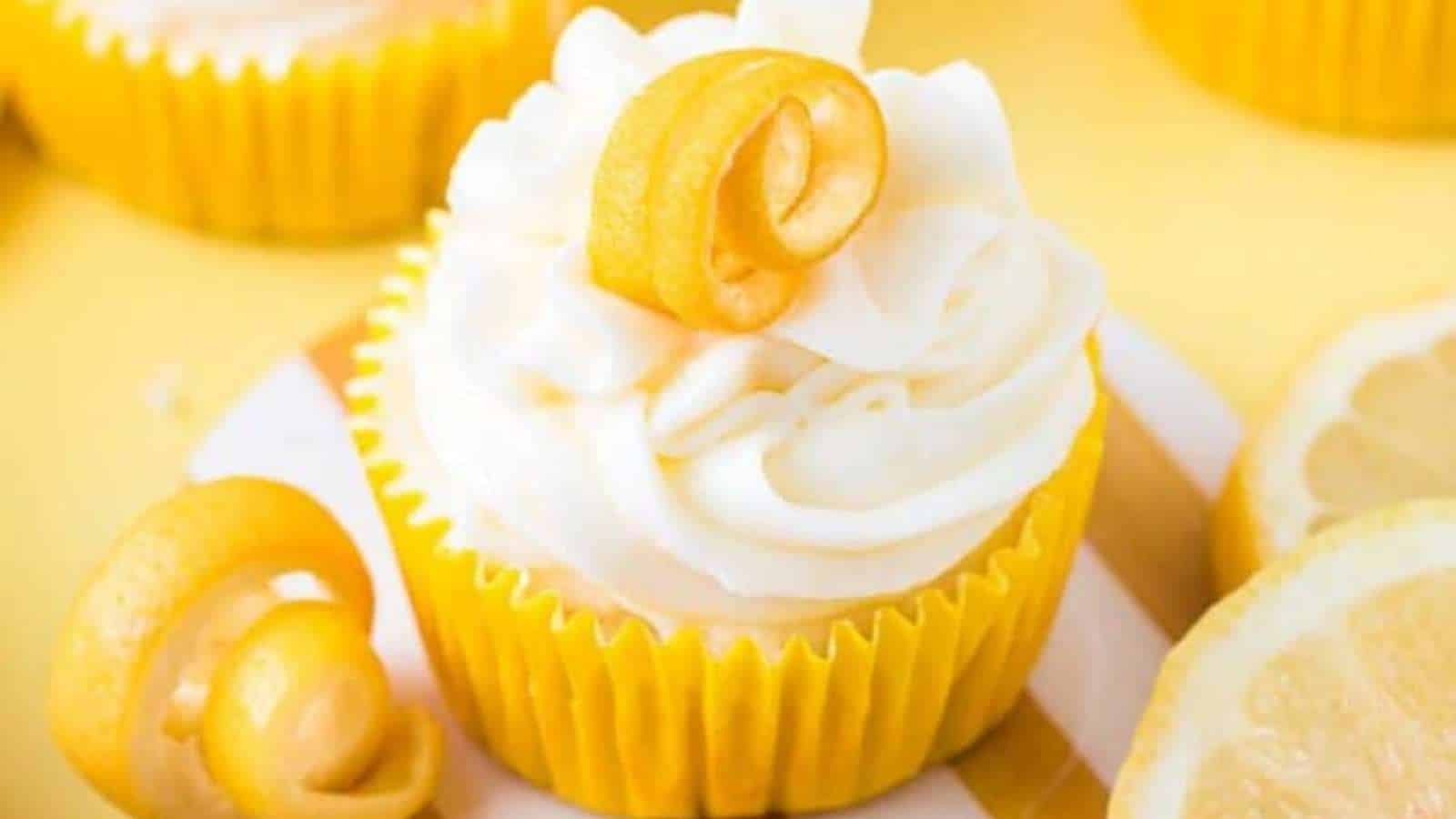 Lemon cupcakes topped with whipped cream and lemon slices.