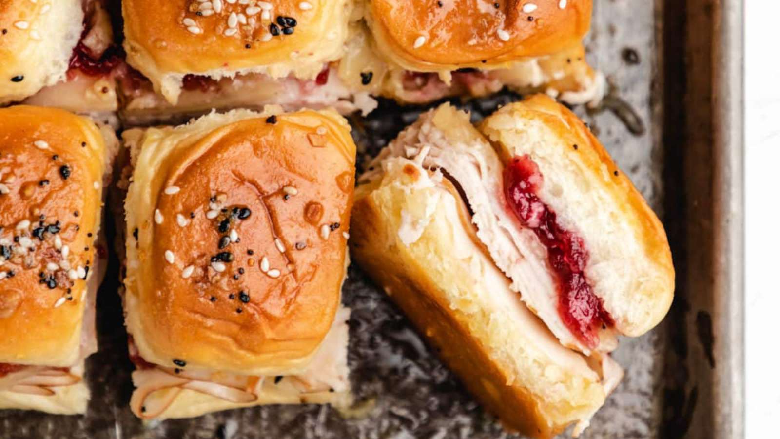 Turkey and cranberry sliders on a baking sheet.