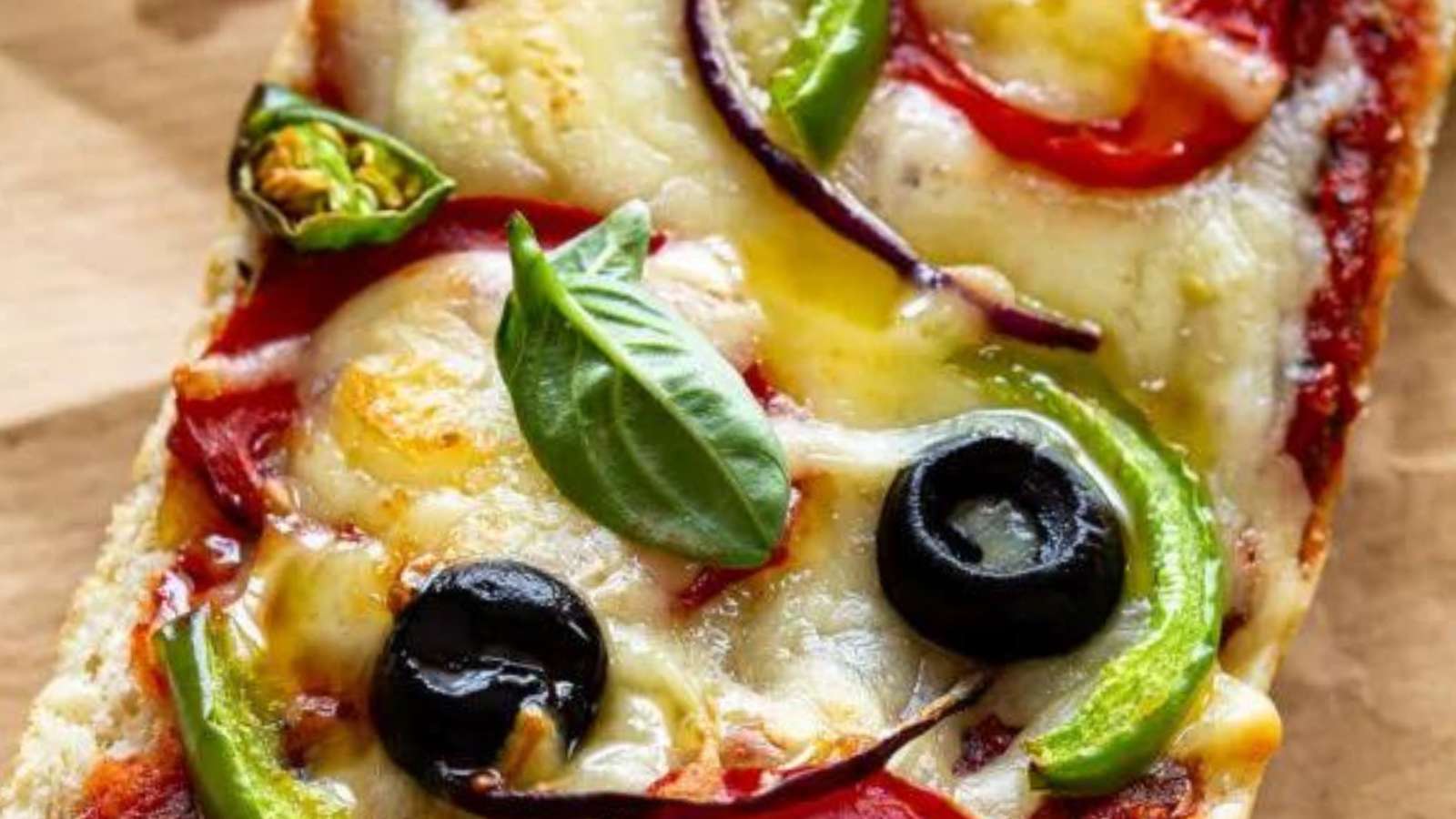 A slice of pizza with olives, tomatoes and basil.