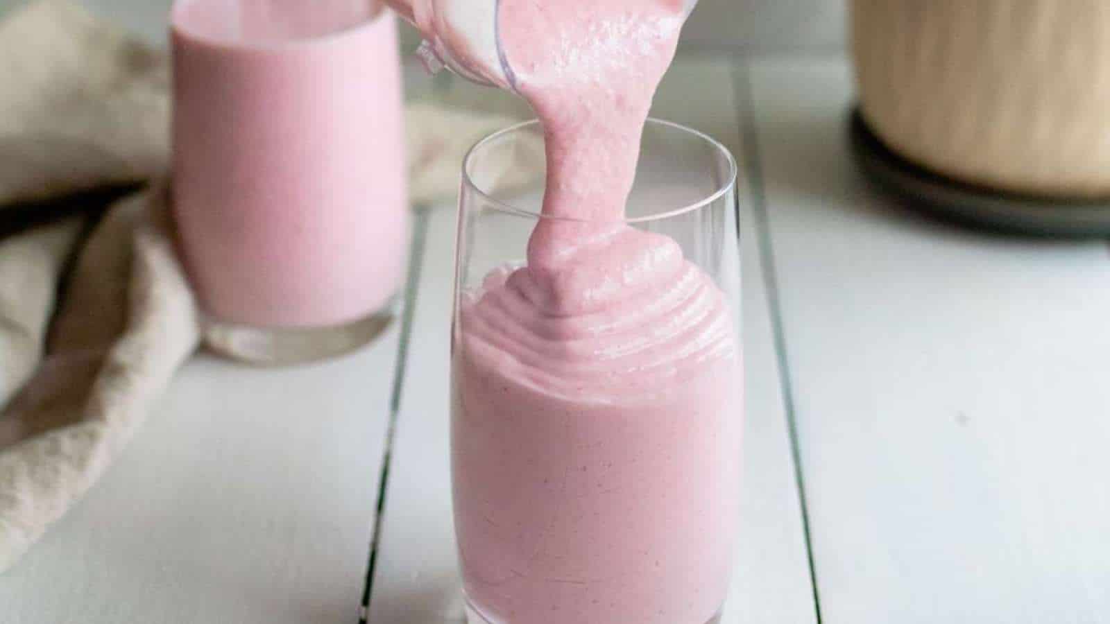 A pink smoothie being poured into a glass.