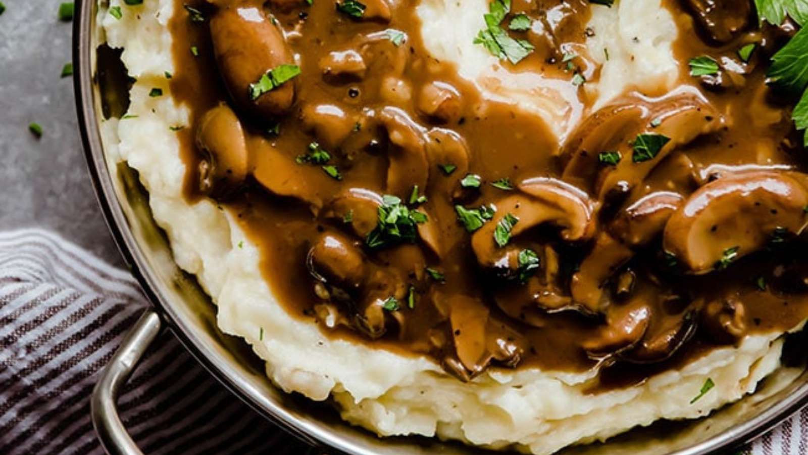 A bowl of mashed potatoes with gravy and mushrooms, enhanced with a touch of Guinness beer.