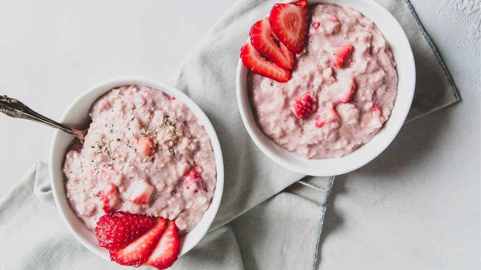 Two bowls of strawberry oatmeal with a spoon.