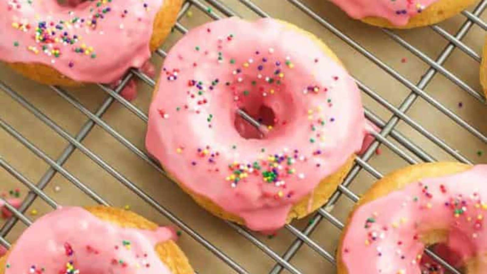 Pink glazed donuts on a cooling rack.