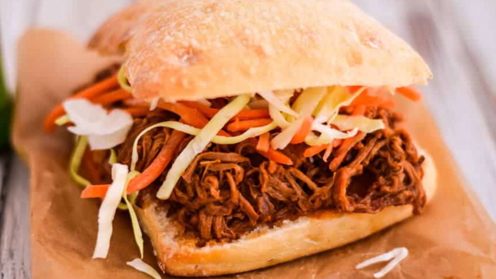A pulled pork sandwich with slaw and carrots.