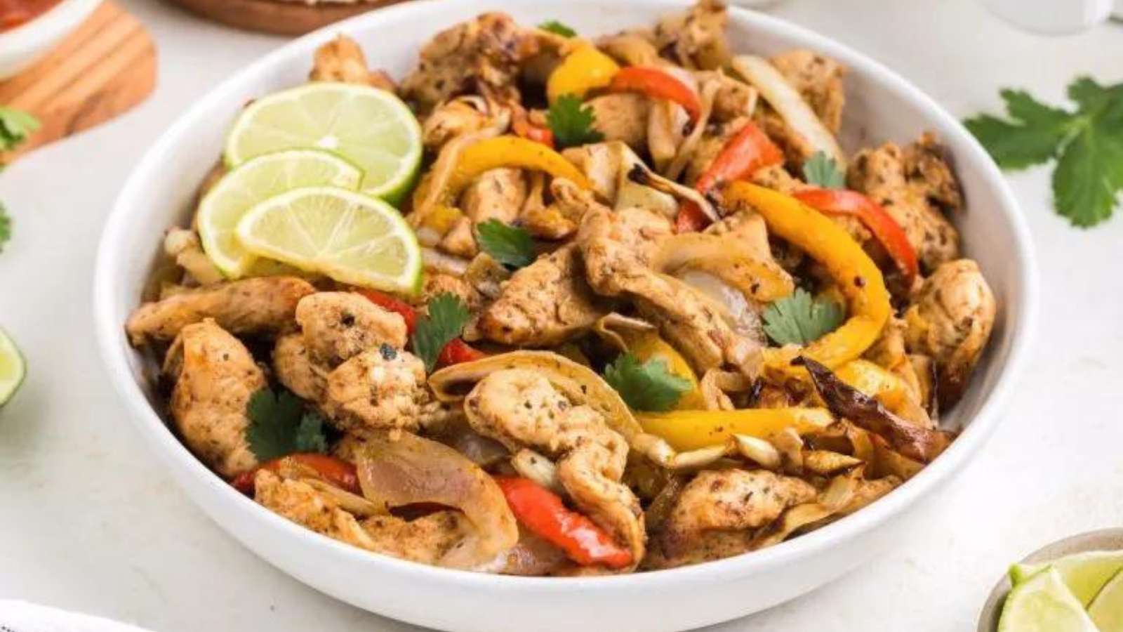Chicken fajitas in a white bowl with peppers and onions.