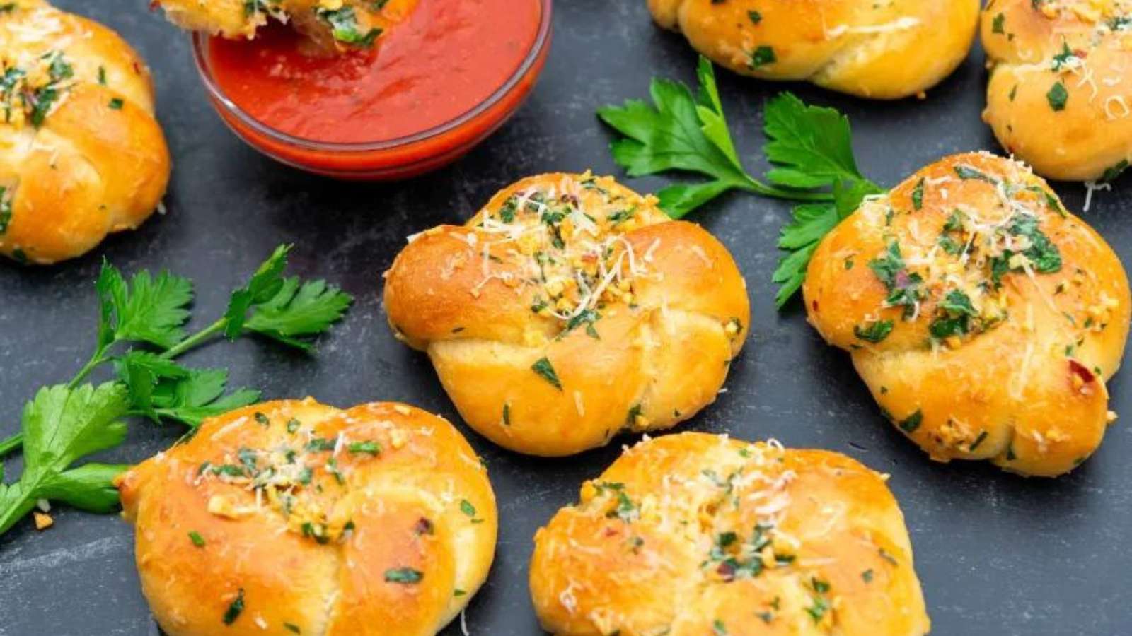 Cheesy garlic knots on a plate with dipping sauce.
