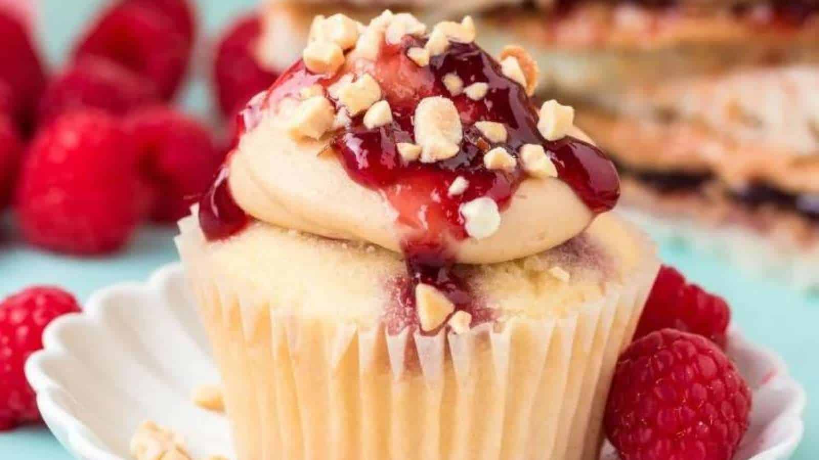 A cupcake with raspberries and nuts on top.