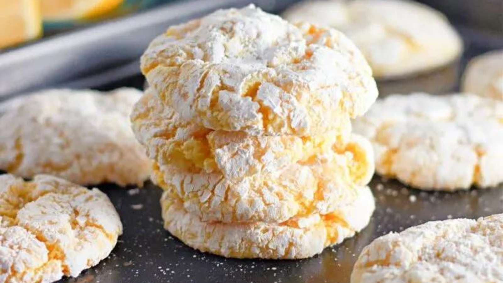A stack of powdered lemon cookies on a baking sheet.