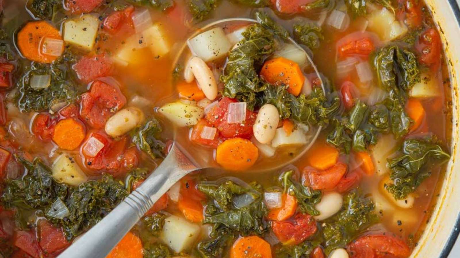 A spoonful of soup with vegetables and beans.