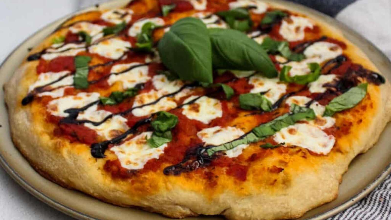 A pizza with sauce and basil on a plate.