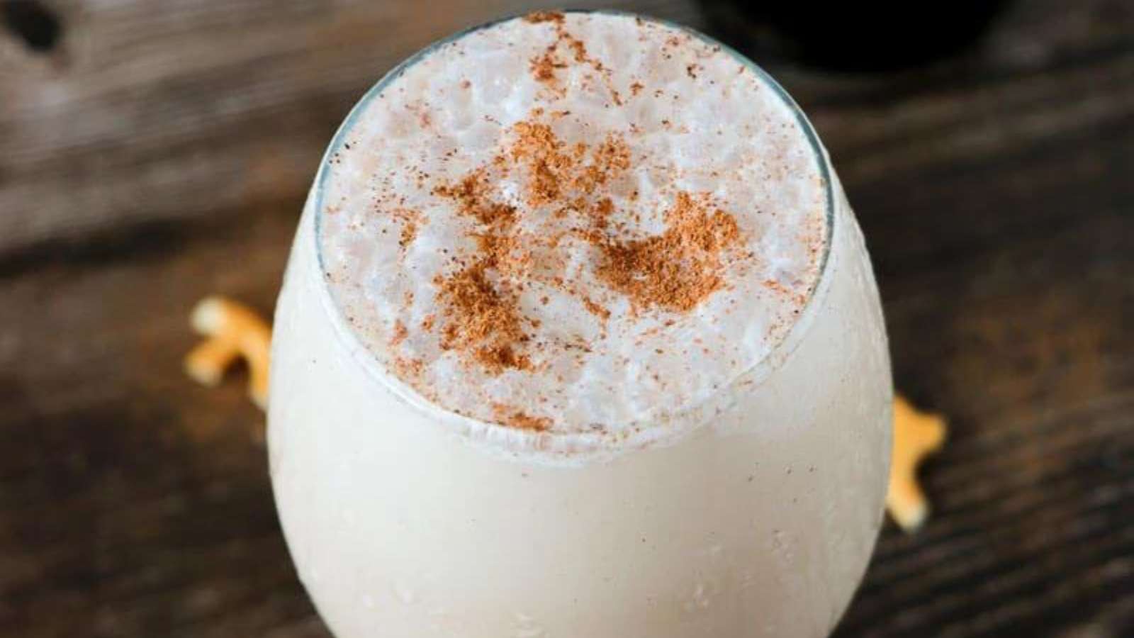 A spiced drink with cinnamon and nutmeg on a wooden table.