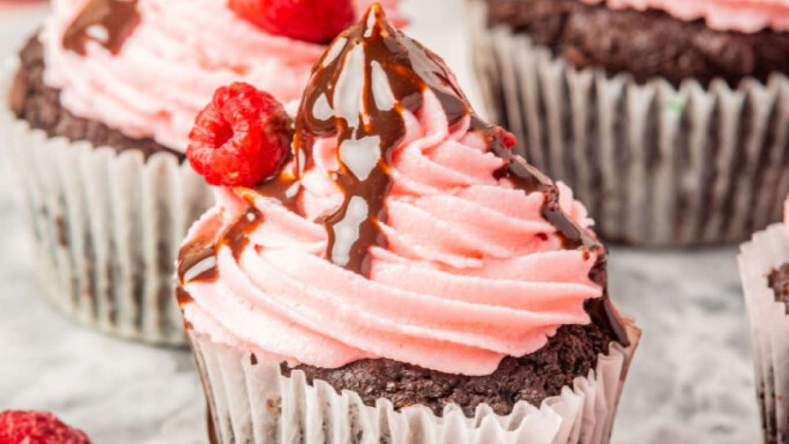 Chocolate cupcakes with raspberries and chocolate icing.