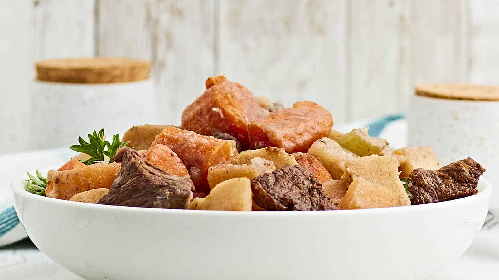 Beef stew in a white bowl on a table.
