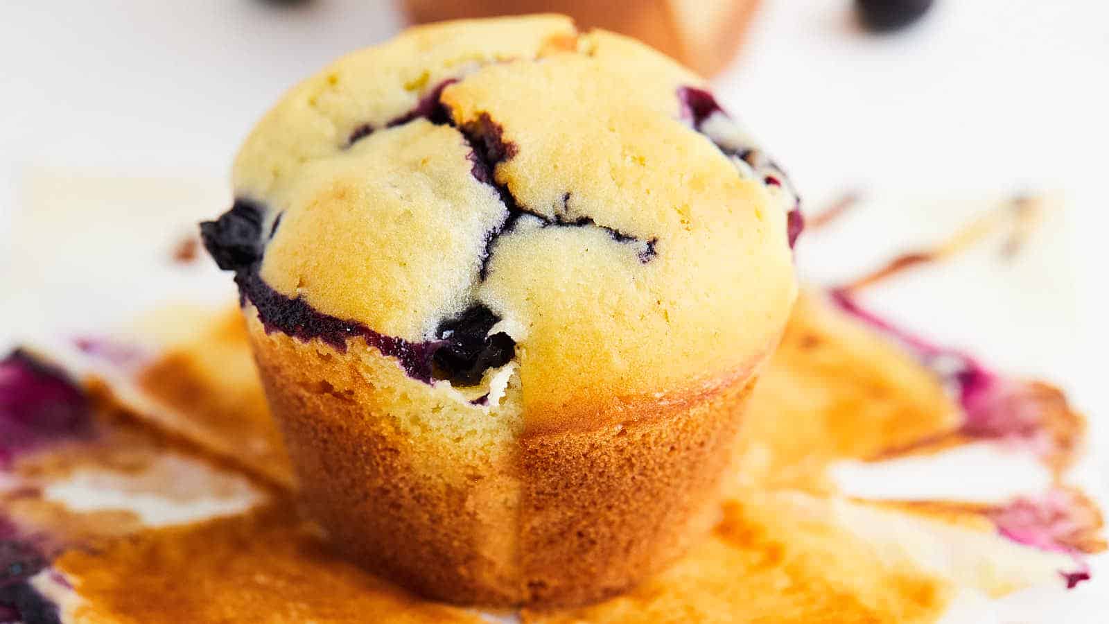 A blueberry muffin is sitting on top of a piece of paper.