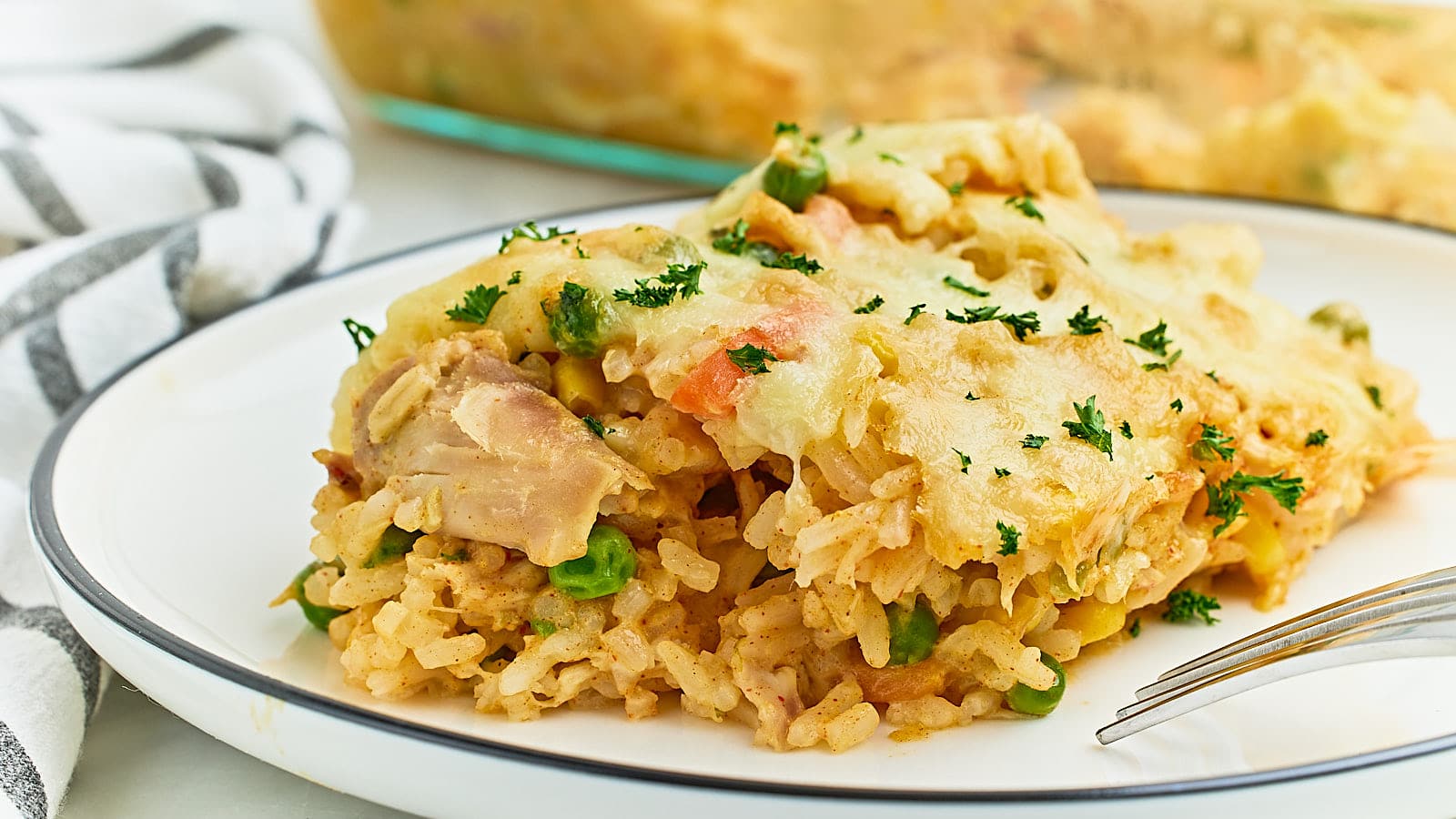 A plate of chicken and rice casserole with a fork.