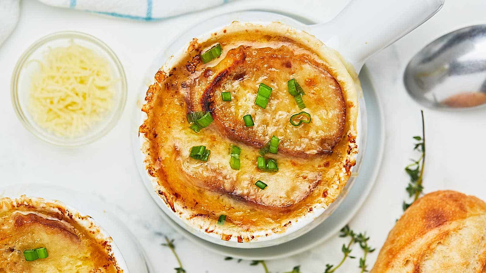 A bowl of french onion soup with bread on the side.