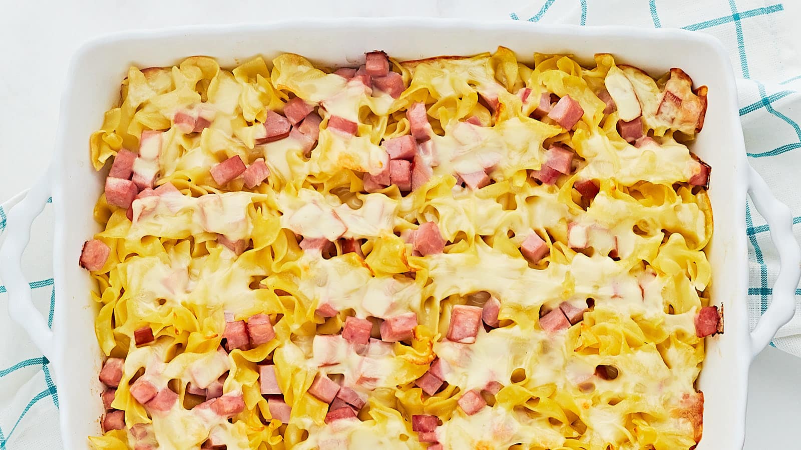 Ham and cheese casserole in a white baking dish.