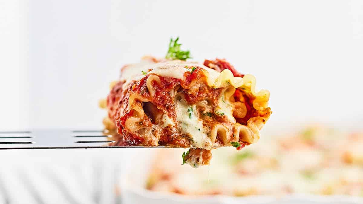A fork is holding a piece of lasagna.