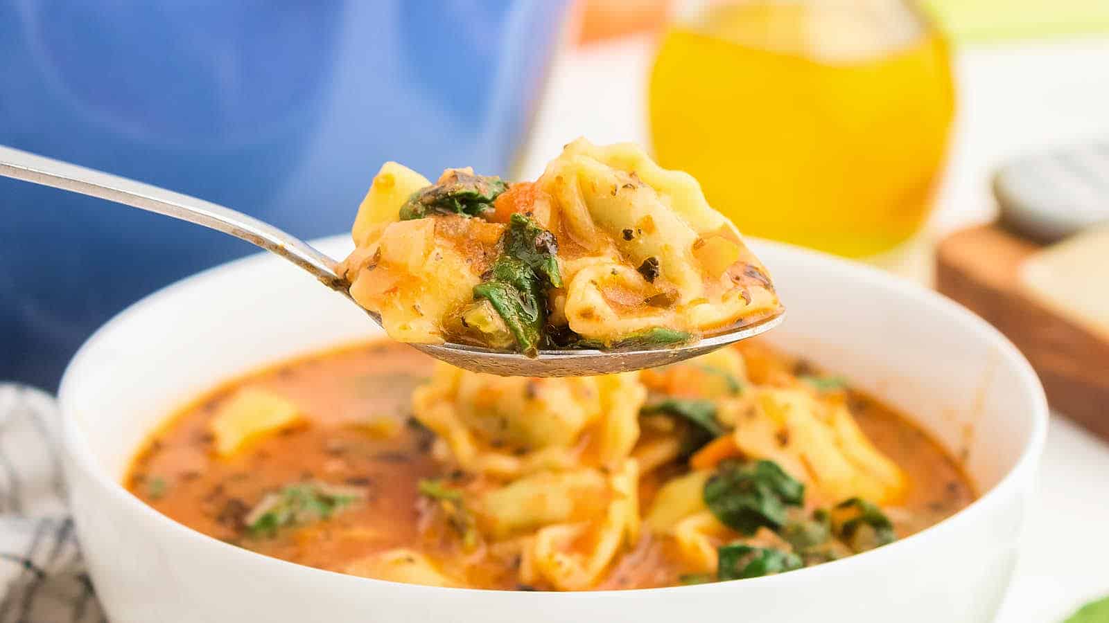 Tortellini soup in a bowl with a spoon.