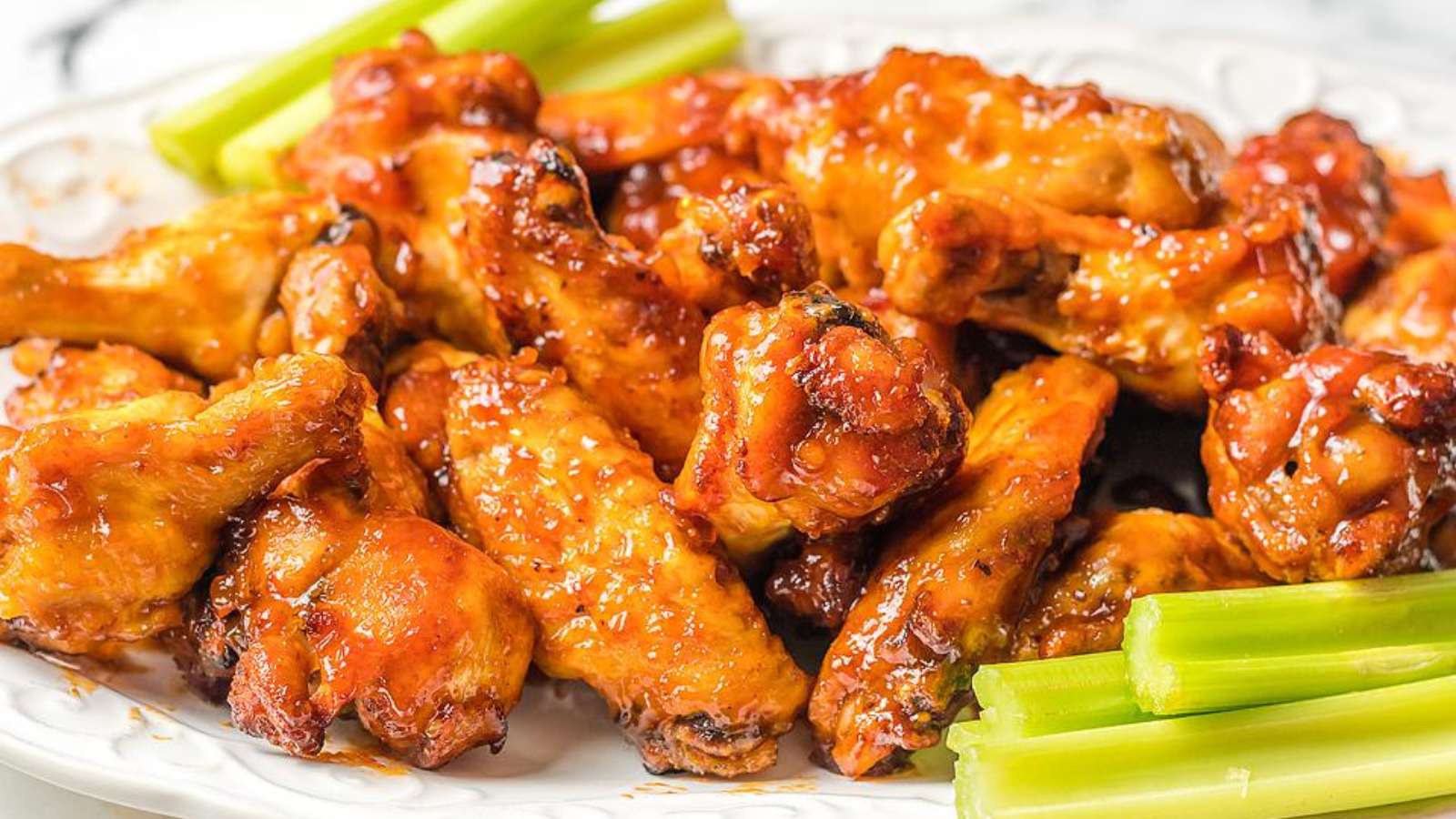 Chicken wings on a plate with celery and celery sticks.