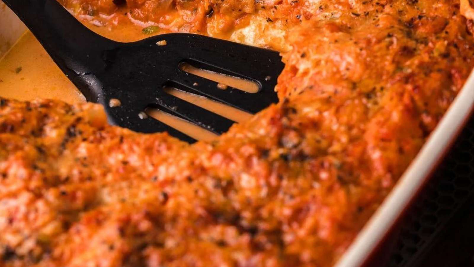 A casserole dish with a spatula in it and Italian Eggplant Parmigiana With Vodka Sauce.