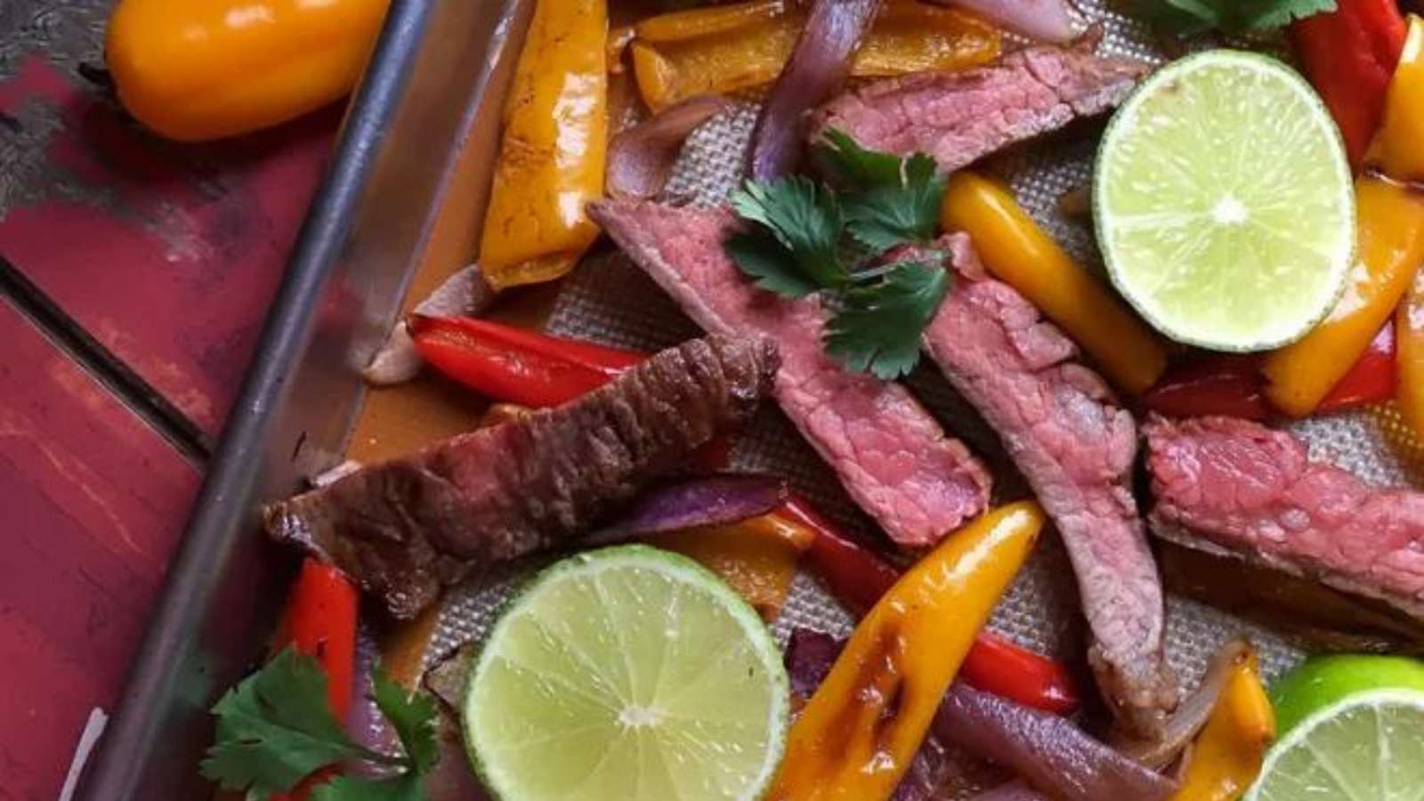 Steak and peppers on a baking sheet.