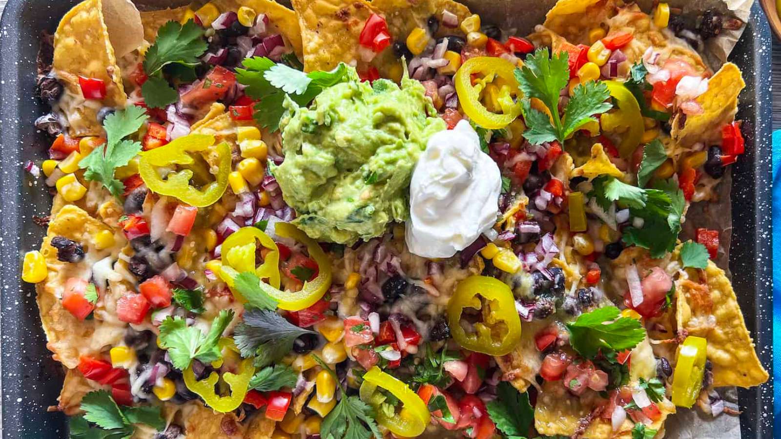 Nachos on a tray with guacamole and sour cream.