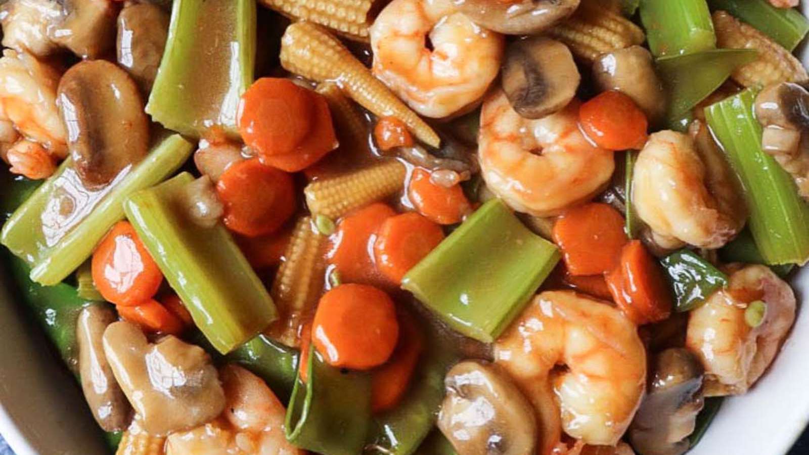 A bowl of stir fried vegetables with shrimp and mushrooms.