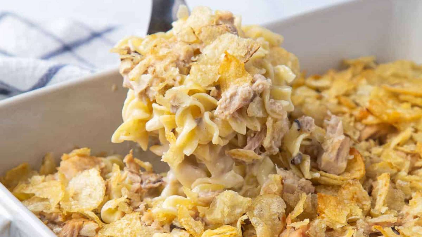 A casserole dish with a scoop of chicken noodle casserole.
